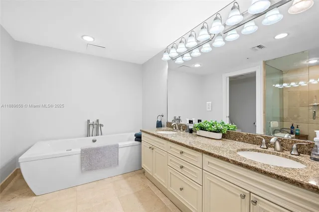 a spacious bathroom with a double vanity sink mirror and bathtub