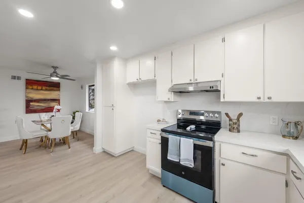 a kitchen with stainless steel appliances white cabinets and a stove top oven