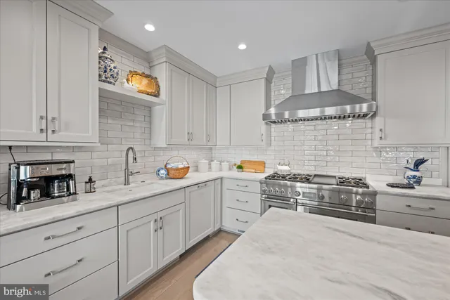a kitchen with stainless steel appliances white cabinets and a stove top oven