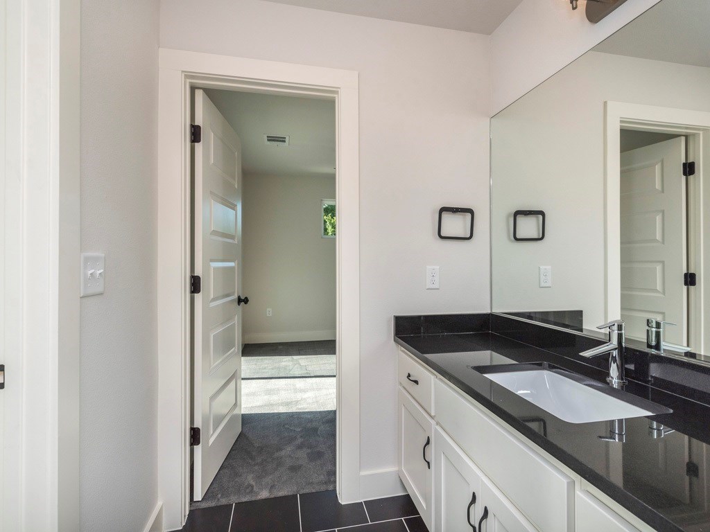 1182 Ridgeway Drive, Unit A Austin, TX 78702 - Photo 23 of 27 a bathroom with a granite countertop sink and a mirror