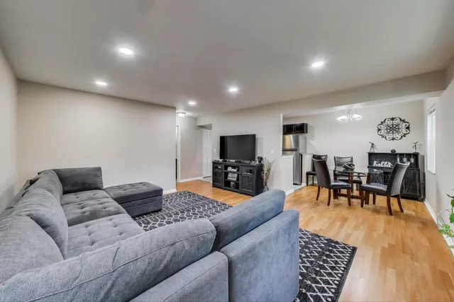 a living room with furniture kitchen view and a wooden floor