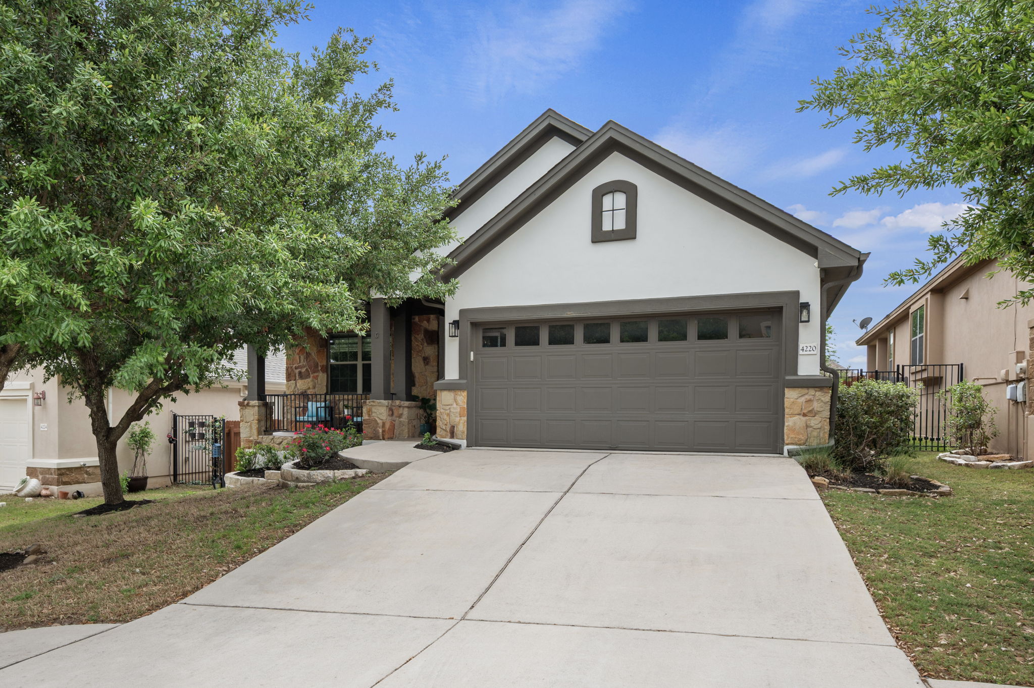 4220 Tambre Bend Austin, TX 78738 - Photo 1 of 1 View of front facade with stone siding, concrete driveway, a garage, and stucco siding