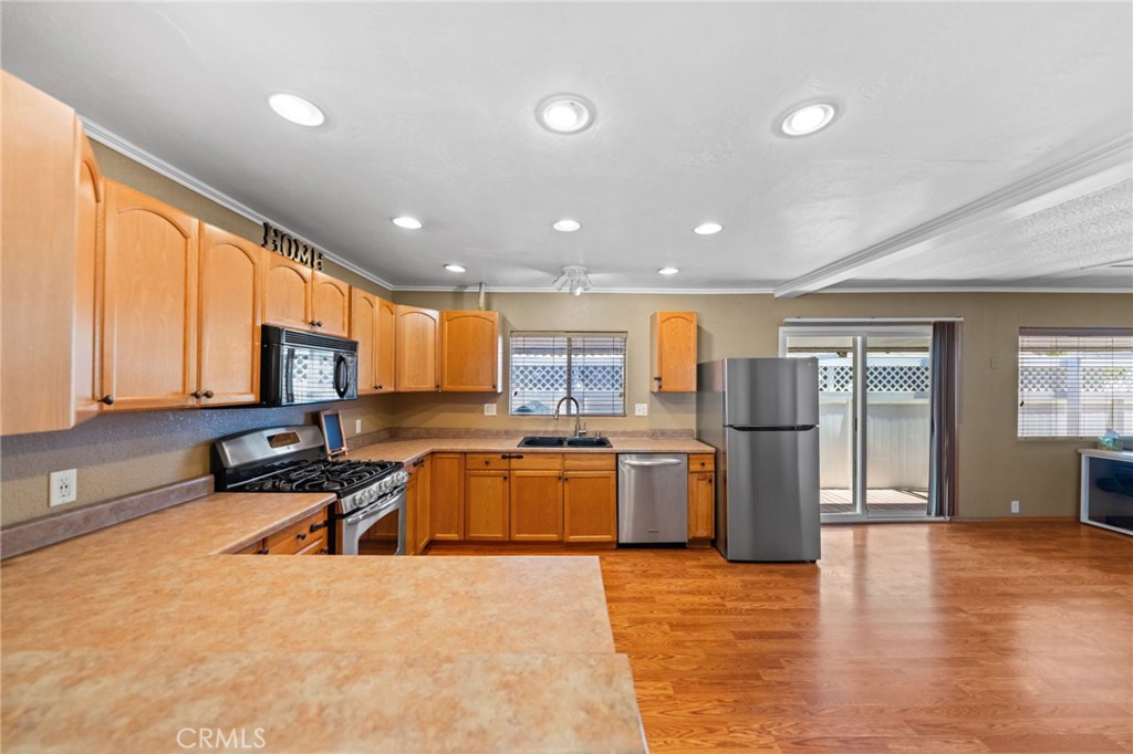 a kitchen with stainless steel appliances granite countertop a refrigerator a sink a stove and oven with wooden floor