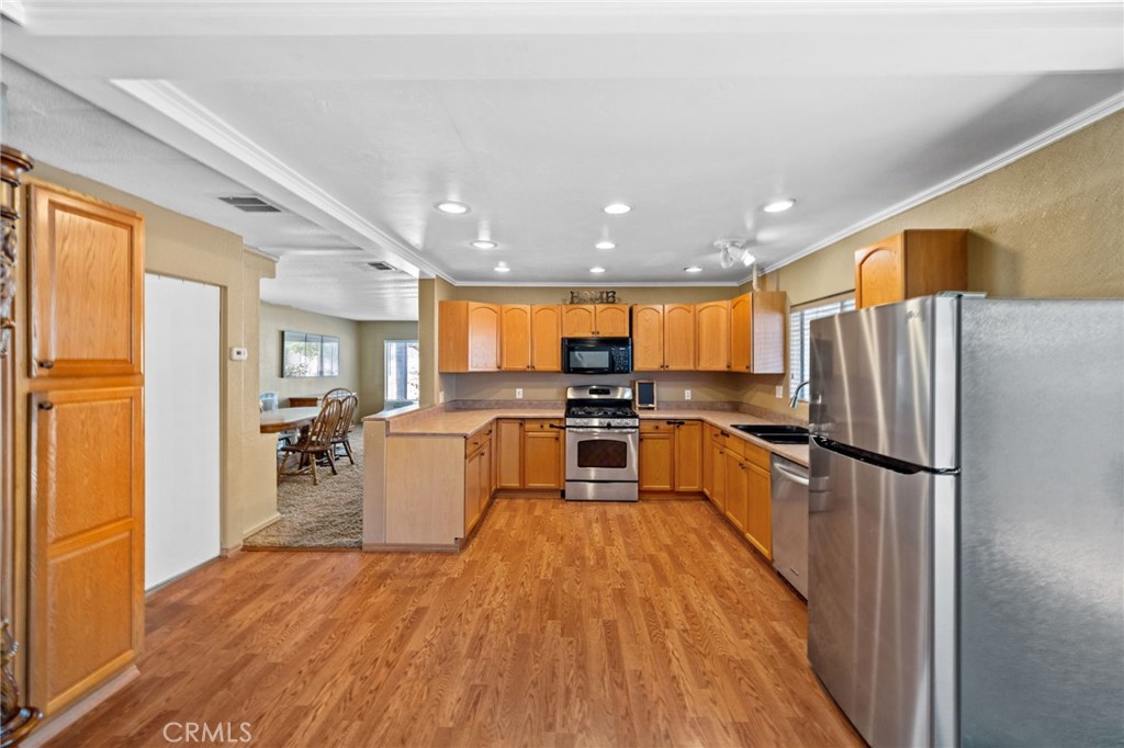 26311 Jackson Avenue, Unit 35 Murrieta, CA 92563 - Photo 9 of 41 a kitchen with a refrigerator a stove top oven a sink dishwasher and wooden cabinets with wooden floor