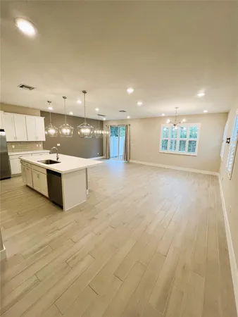 a large white kitchen with kitchen island a sink stainless steel appliances and cabinets
