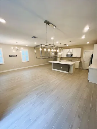 a view of a kitchen with kitchen island stainless steel appliances wooden floor and living room view
