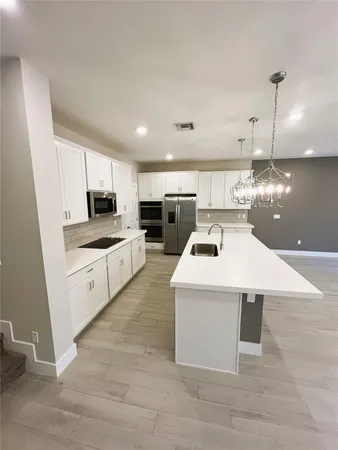 a kitchen with kitchen island a white counter top space cabinets and stainless steel appliances