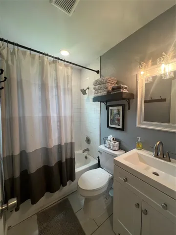 a bathroom with a sink a toilet a mirror and shower curtain