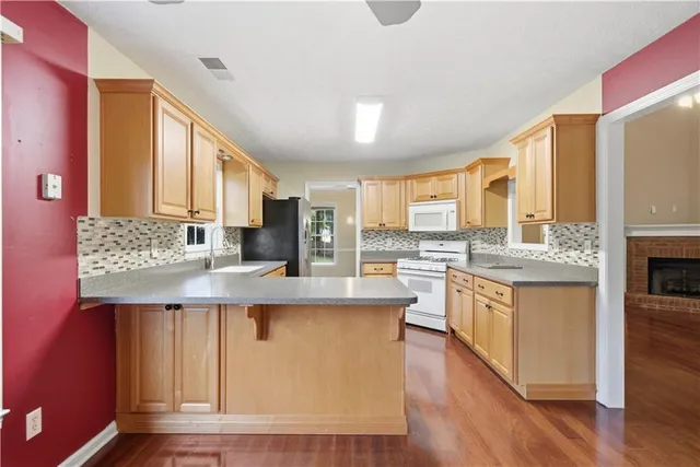 a kitchen with stainless steel appliances granite countertop a stove a sink dishwasher and a refrigerator with wooden floor