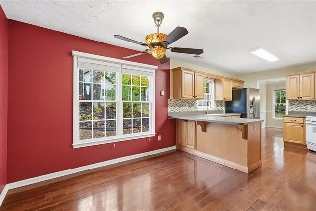 a view of an empty room with window and kitchen view