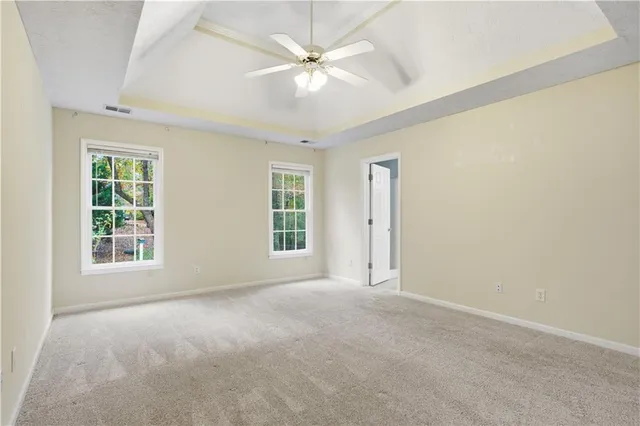 an empty room with windows and ceiling fan