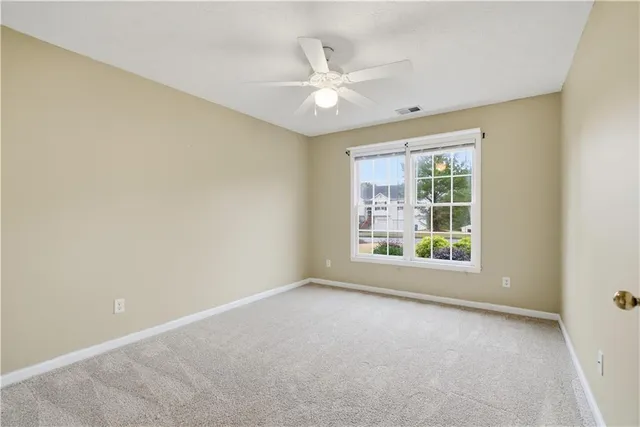 an empty room with windows and ceiling fan