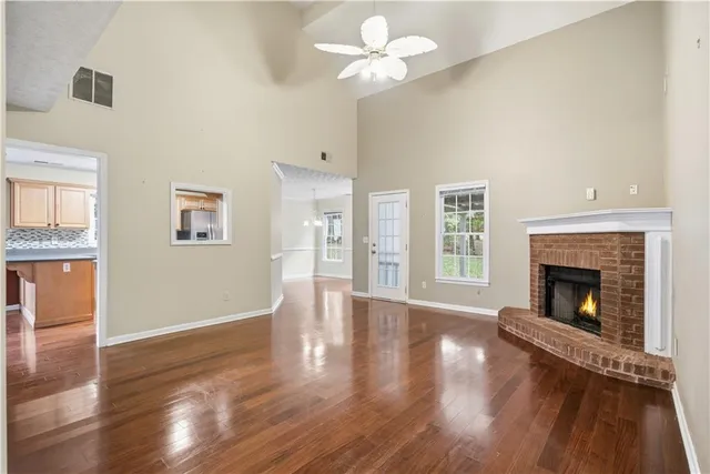 a view of an empty room with wooden floor and a fireplace