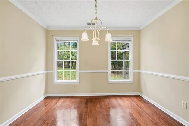 an empty room with wooden floor windows and entrance