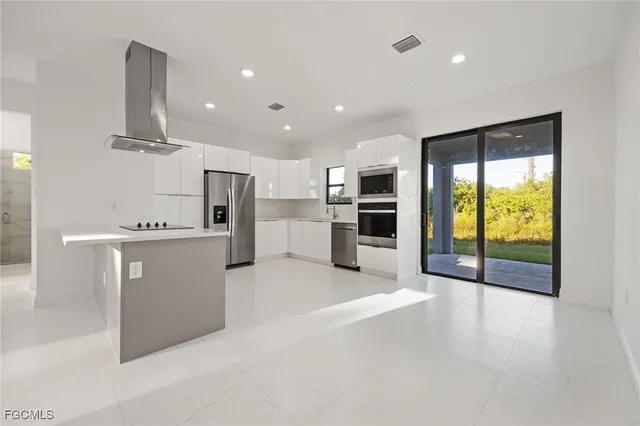 a large kitchen with stainless steel appliances granite countertop a refrigerator and a stove top oven