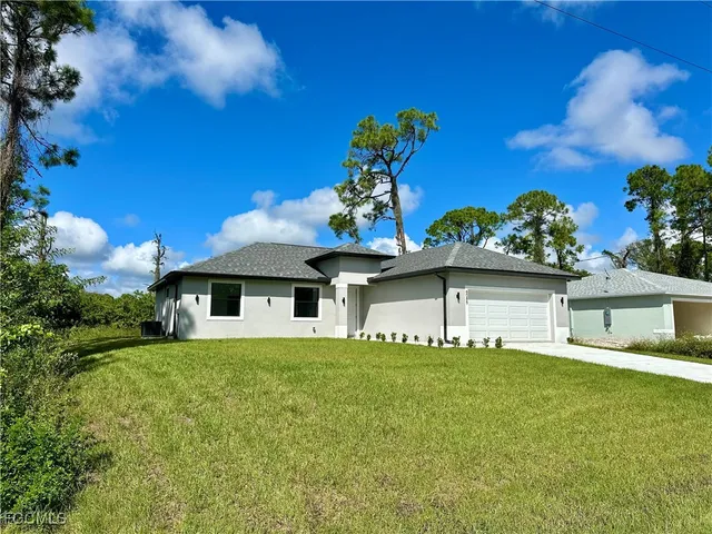 a white house with a big yard and large trees