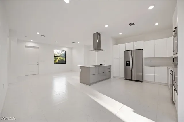 a kitchen with stainless steel appliances kitchen island a refrigerator and a counter top space