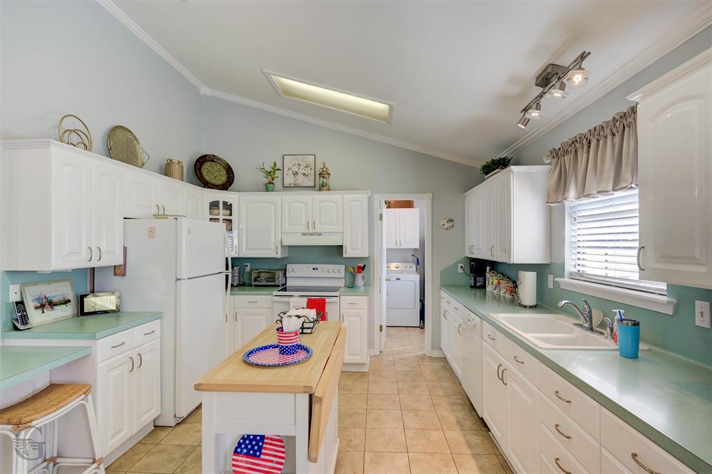 8835 Sebastian Road Keithville, LA 71047 - Photo 8 of 21 White cabinetry, vaulted ceiling, skylight, tile flooring, and track lighting