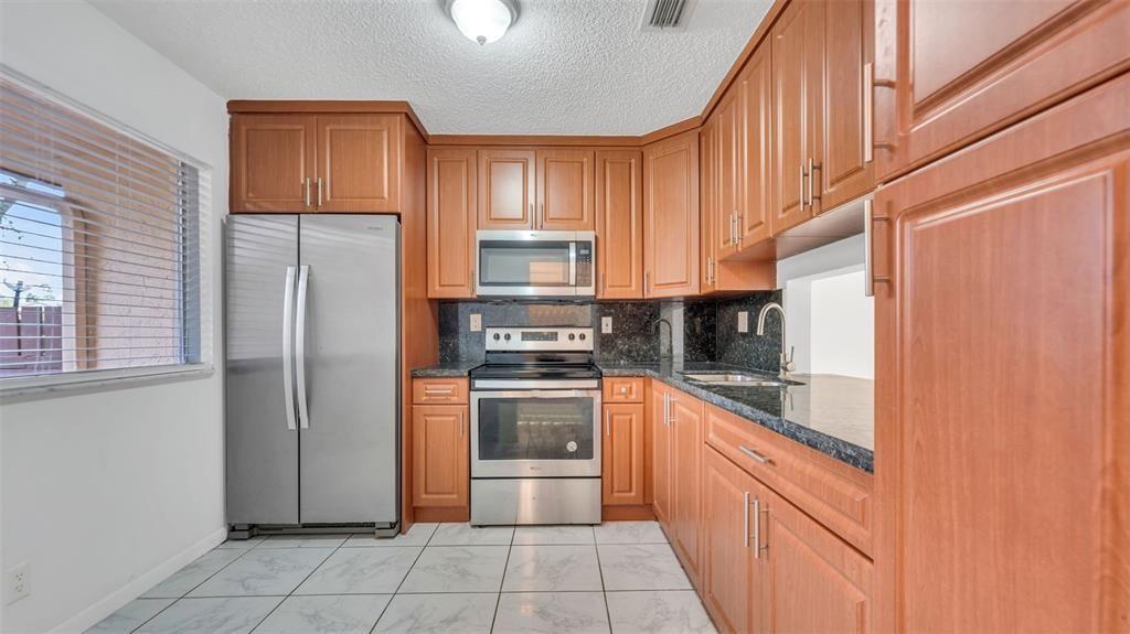 1153 Hampton Boulevard North Lauderdale, FL 33068 - Photo 2 of 10 a kitchen with stainless steel appliances granite countertop a refrigerator and a stove top oven