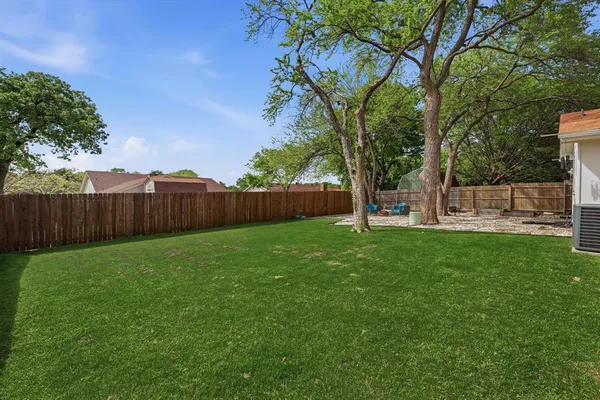 a view of a backyard with a large tree and wooden fence