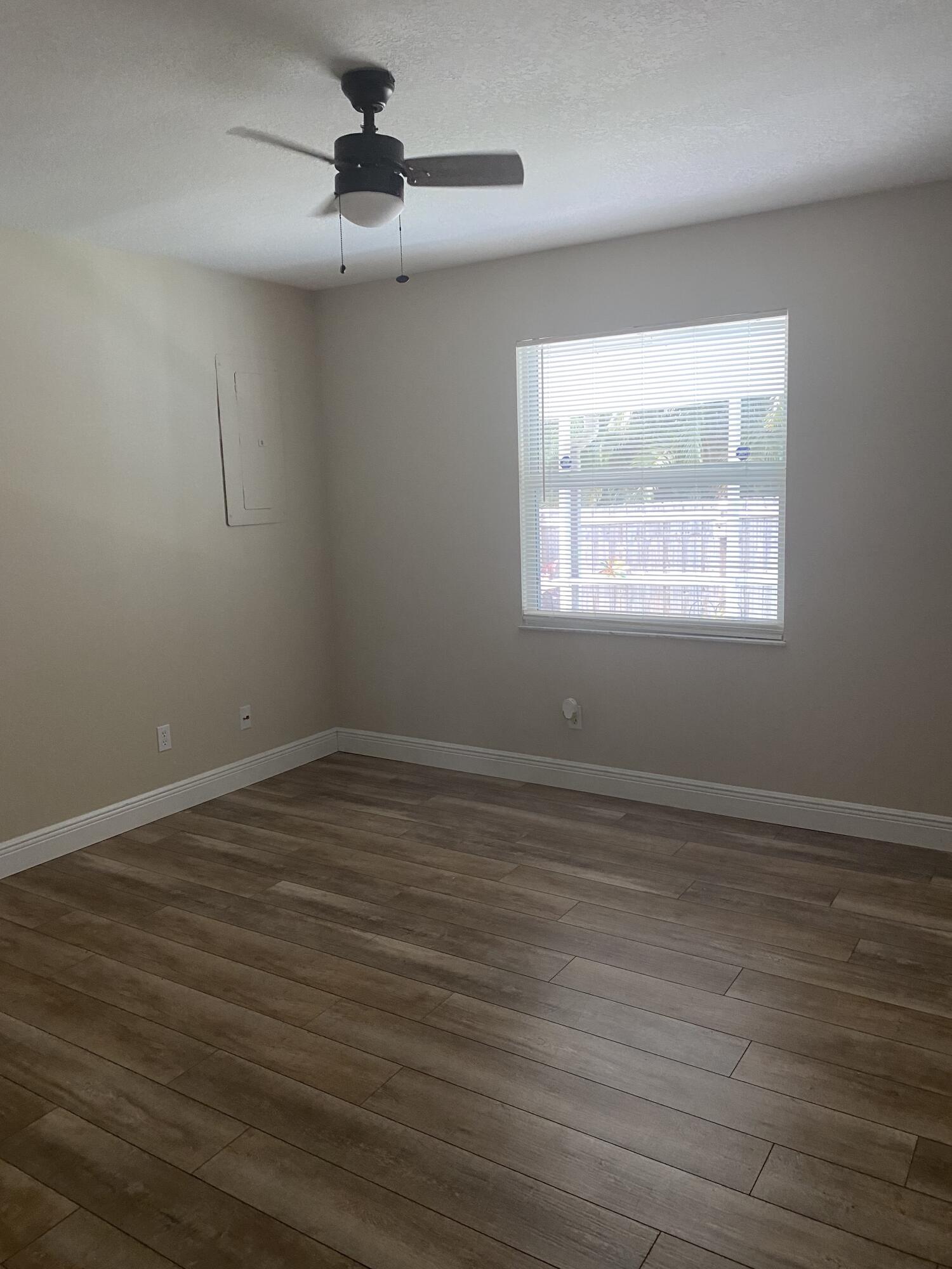 3196 Southwest Areca Drive Palm City, FL 34990 - Photo 15 of 21 an empty room with wooden floor chandelier fan and windows