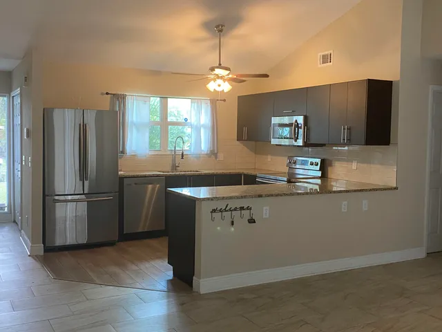 a kitchen with stainless steel appliances granite countertop a refrigerator a sink dishwasher a stove and a refrigerator