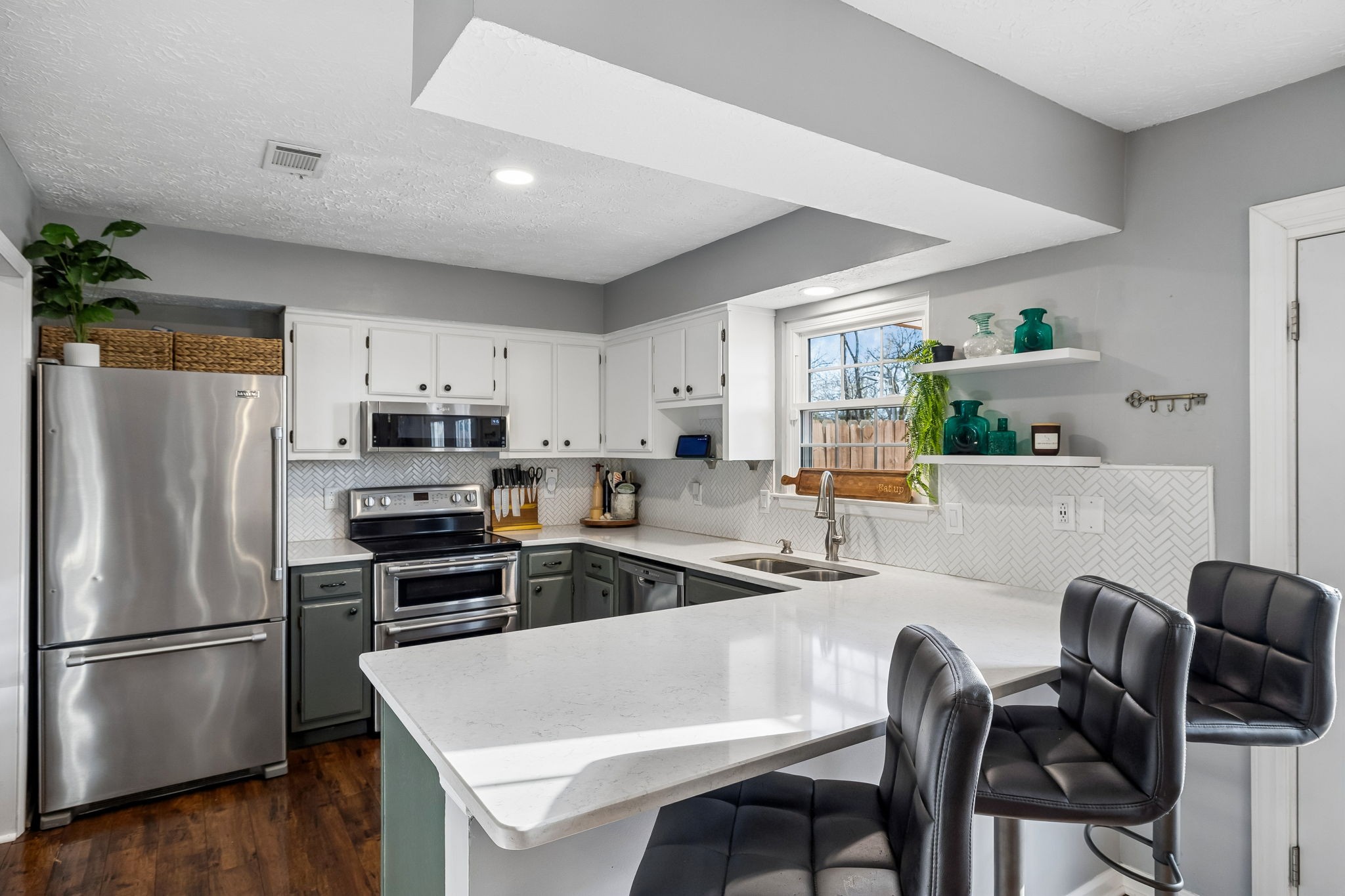 a kitchen with stainless steel appliances a refrigerator a stove a sink dishwasher a dining table and chairs with wooden floor