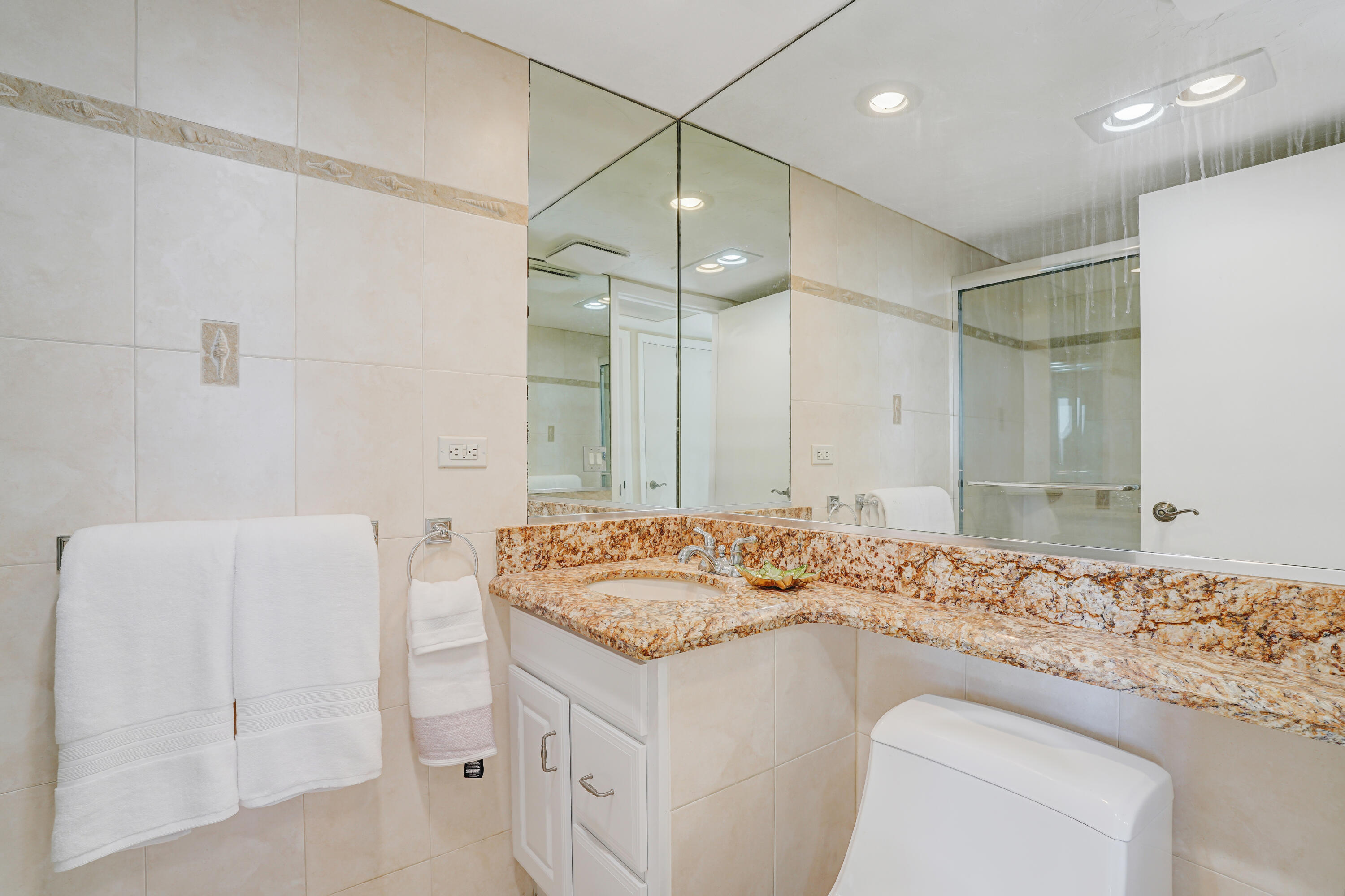 1208 Marine Way, Unit 602 North Palm Beach, FL 33408 - Photo 16 of 25 a bathroom with a granite countertop sink a toilet and a mirror