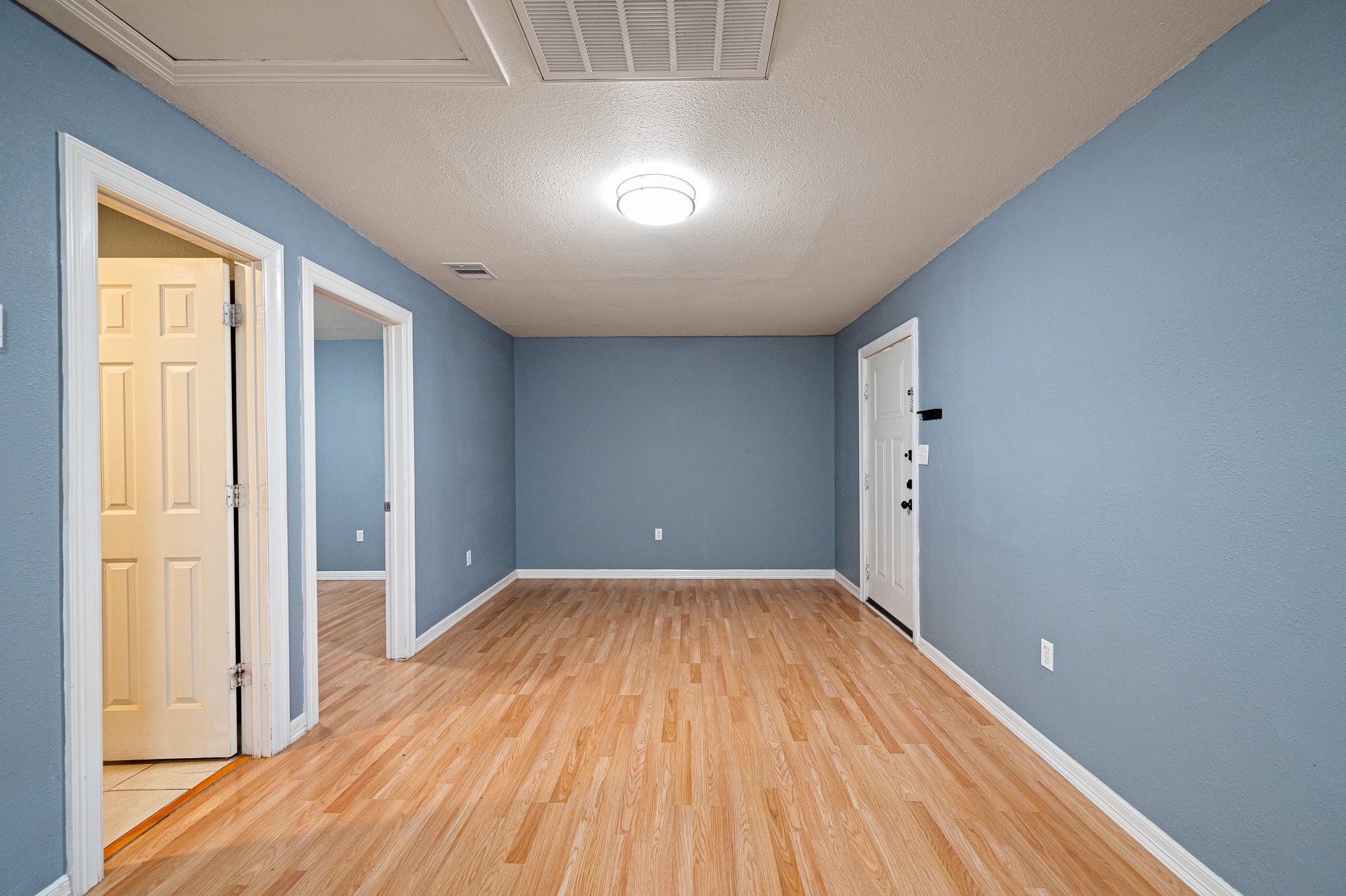 7815 Harding Street, Unit B Houston, TX 77012 - Photo 10 of 21 From the kitchen, enjoy a seamless view into the inviting living room, featuring elegant flooring and a soothing blue palette, perfect for modern living.