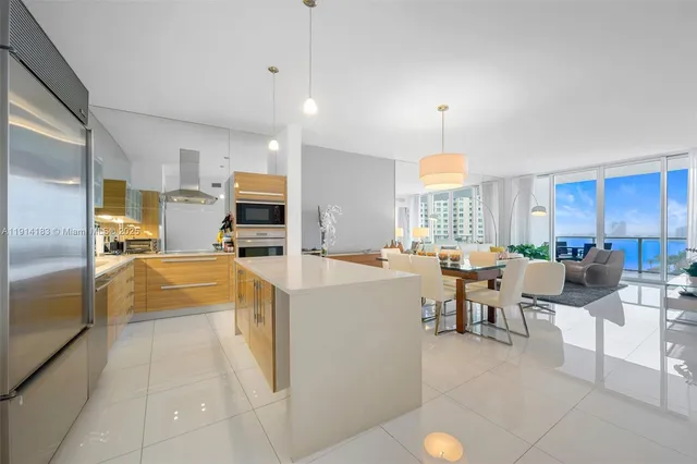 a large white kitchen with lots of counter top space a sink stainless steel appliances and cabinets