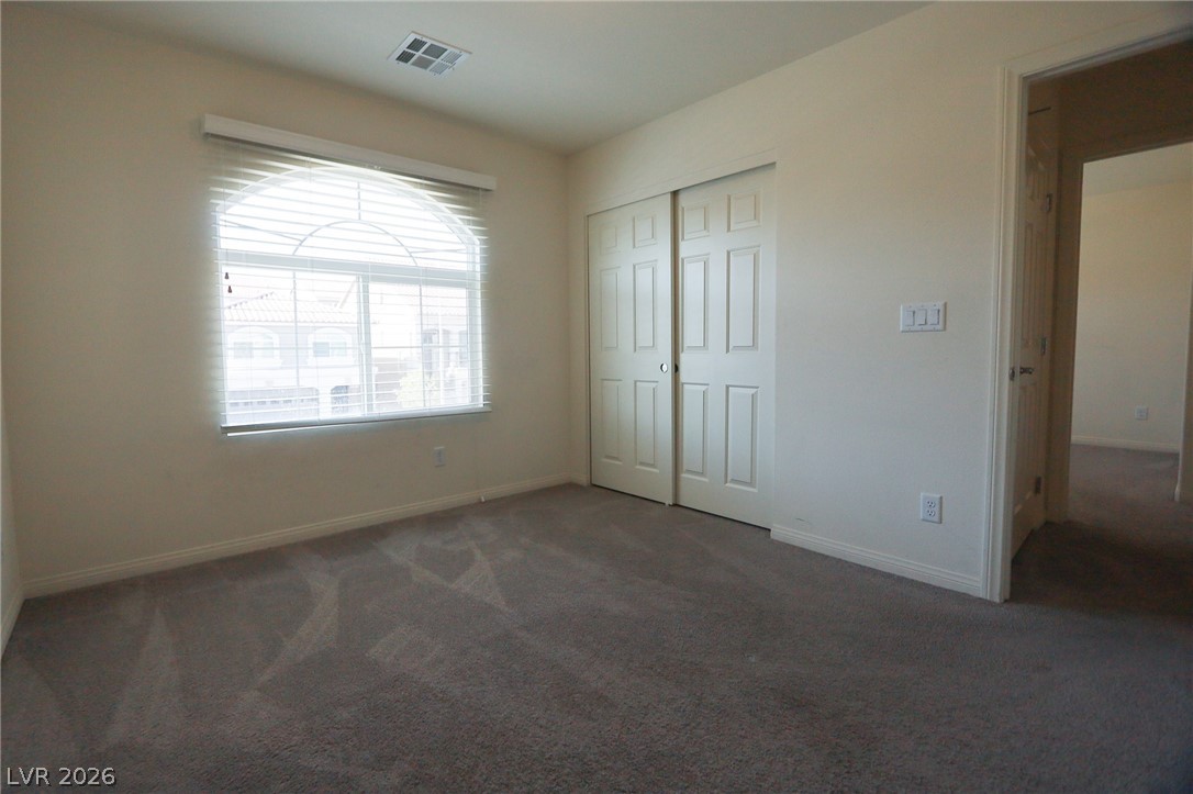 6418 Jackson Spring Road Las Vegas, NV 89118 - Photo 11 of 20 A well-lit bedroom features plush carpeting and a large arched window with blinds.