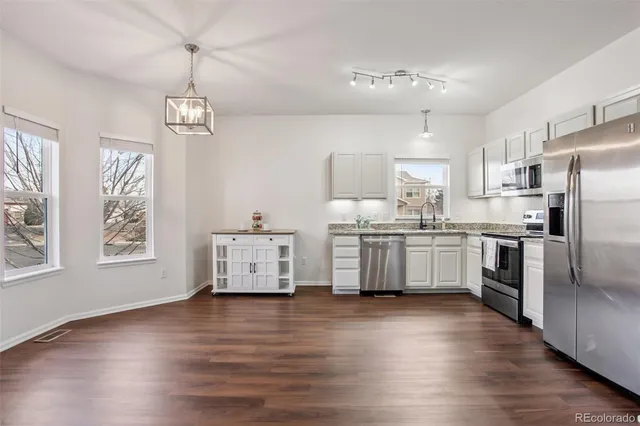 a kitchen with stainless steel appliances a refrigerator sink cabinets and wooden floor