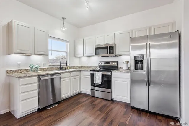 a kitchen with kitchen island granite countertop a refrigerator and a sink