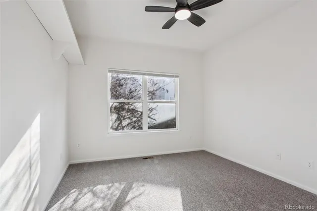 an empty room with a window and a ceiling fan