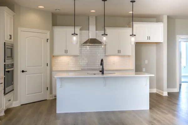 a large kitchen with stainless steel appliances kitchen island granite countertop a sink a counter and a refrigerator