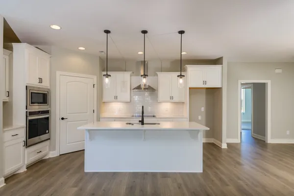 a large white kitchen with a large window a sink and stainless steel appliances