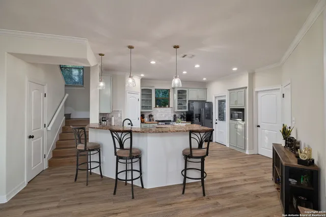 a kitchen with stainless steel appliances a dining table chairs wooden floor and a refrigerator