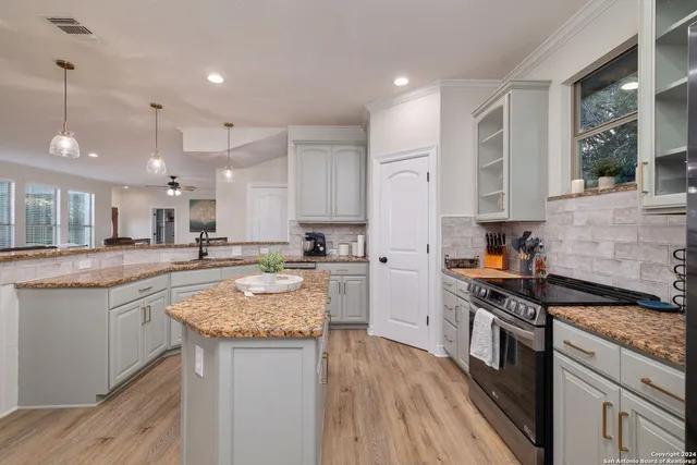 a kitchen with stainless steel appliances granite countertop wooden floor sink stove and granite counter top