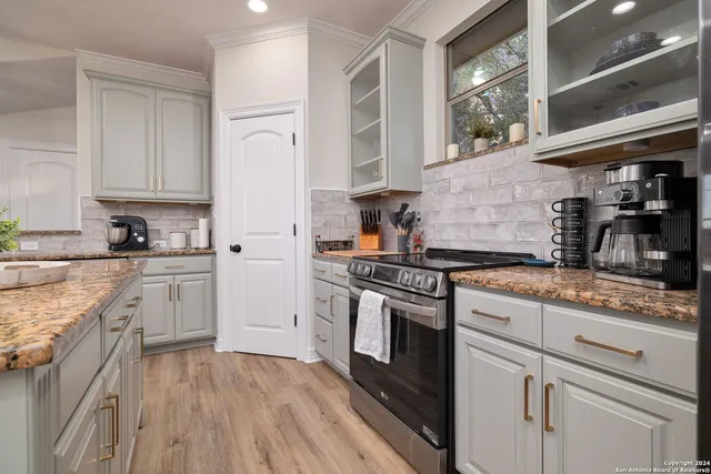 a kitchen with stainless steel appliances granite countertop a stove a sink and white cabinets