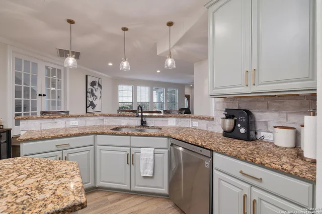 a kitchen with granite countertop a sink a counter space appliances and cabinets