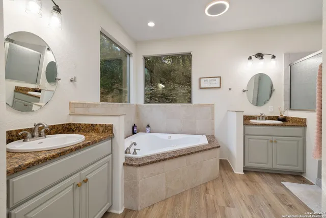 a bathroom with a double vanity sink mirror and bathtub