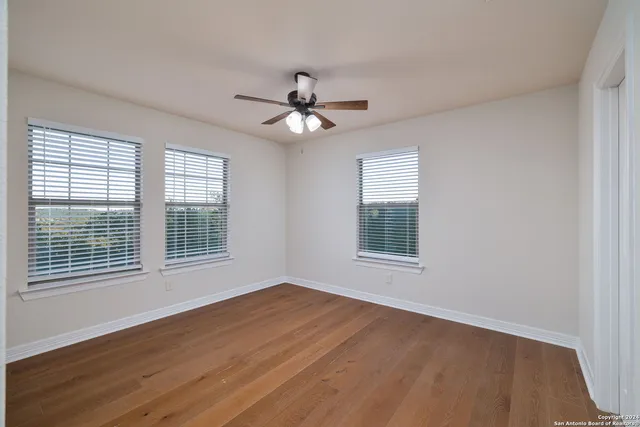 a view of an empty room with a window and wooden floor