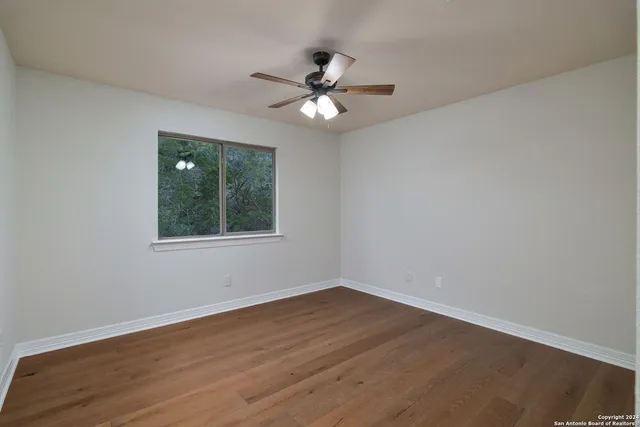 a view of a room with wooden floor a chandelier fan and windows