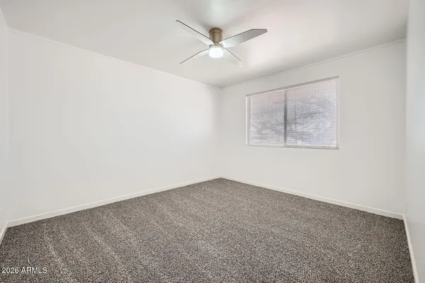 an empty room with a chandelier fan and windows