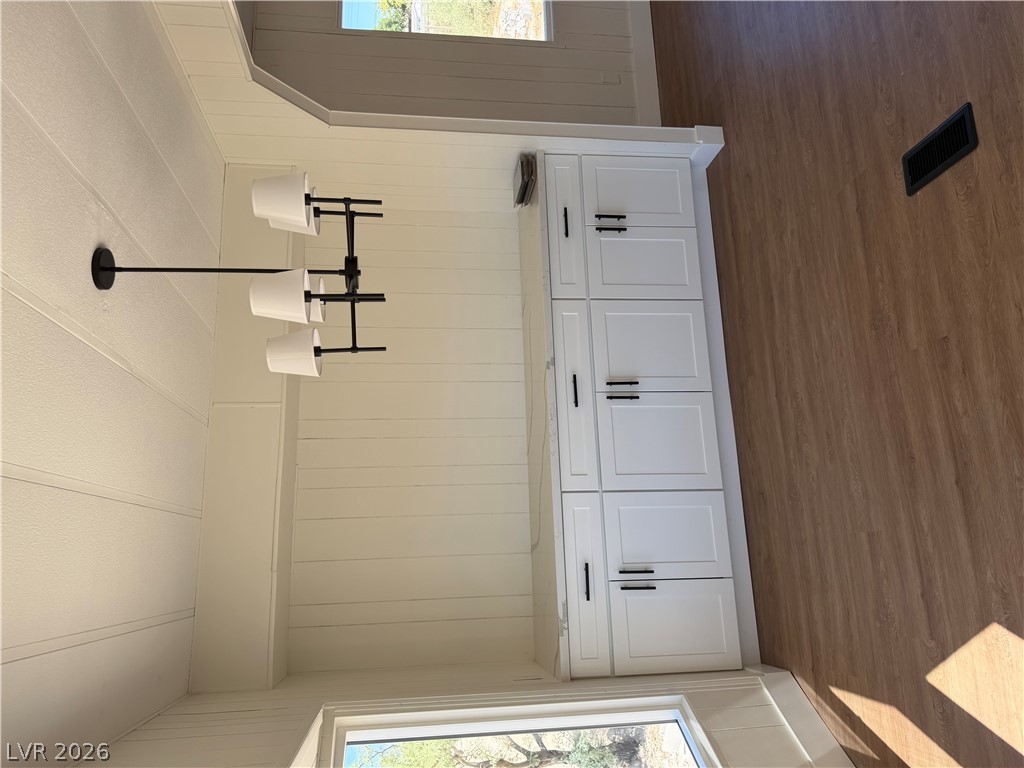 6401 Hafen Ranch Road Pahrump, NV 89061 - Photo 13 of 22 Warm wood-toned floors anchor this bright transition space featuring a classic white built-in sideboard.