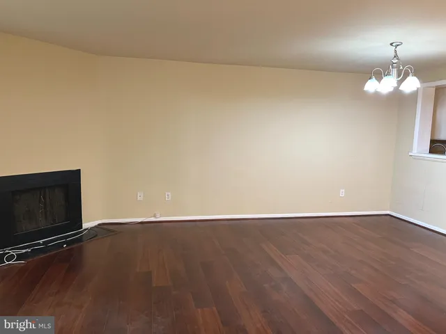 a view of an empty room with wooden floor and a fireplace