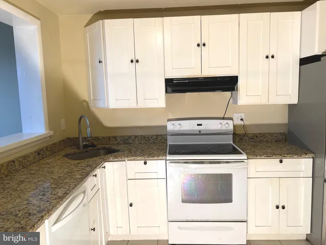a kitchen with granite countertop a stove a sink and a microwave