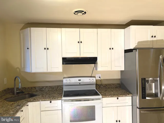 a kitchen with granite countertop a stove a refrigerator and a sink