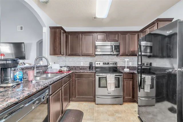 a kitchen with stainless steel appliances granite countertop a sink stove and microwave