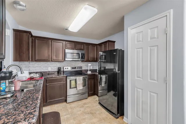 a kitchen with stainless steel appliances granite countertop a refrigerator stove and sink